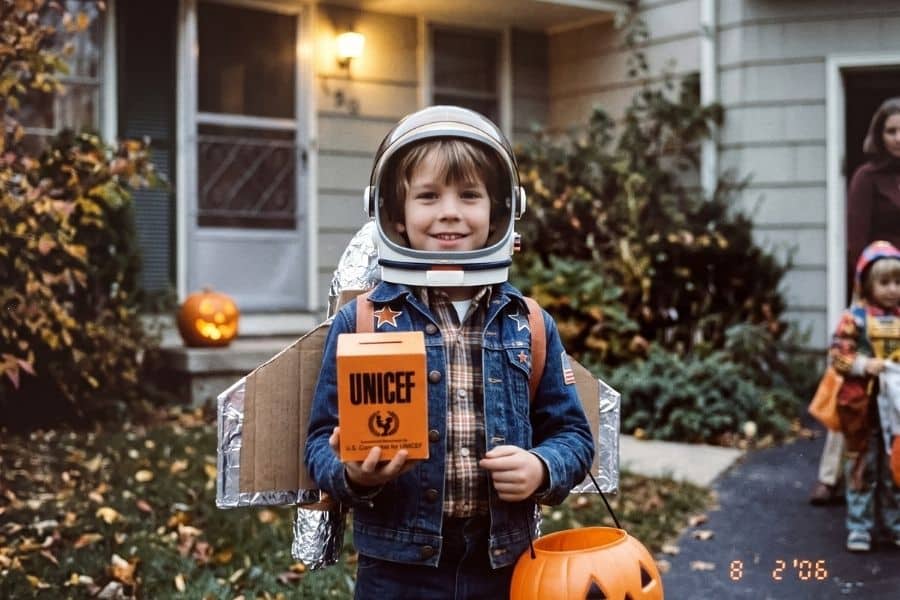 Child in a Halloween costume holding an orange Trick-or-Treat for UNICEF box